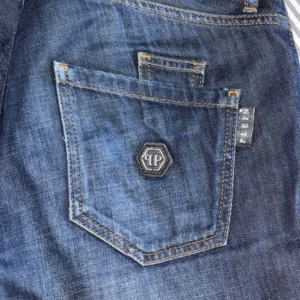 Philipp Plein blå straight jeans - Snygga blå jeans från Philipp Plein med straight cut och slitna detaljer. Klassisk femficksmodell med PP-logga på bakfickan och silverfärgade knappar med märkets namn. Jeansen har kontrastsömmar och är tillverkade i robust denim. Pris går att diskutera.