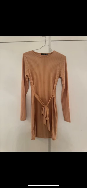 Klänning boohoo - Begie klänning från boohoo. Aldrig användt. Passar xs/s storlek 38. Knyt från sidorna till fram eller bak. Kort upp till knäna ungefär. 