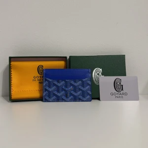 Blå G yard plånbok med mönster - Supersnygg blå plånbok från G yard med deras ikoniska grafiska mönster i vitt och mörkblått. Slimmad design med flera kortfack och detaljer i skinn. Perfekt för dig som vill ha något både stilrent och unikt i fickan.