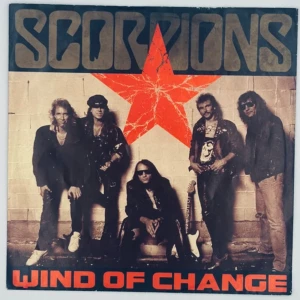 Scorpions - Wind Of Change - 7" Vinyl Singel - Upptäck klassisk rock med Scorpions! 'Wind of Change' är en ikonisk singel från 1990, perfekt för dig som älskar musik och vill ha en cool vinyl i samlingen. Omslaget har bandet och en stor röd stjärna – ett måste för alla unga rockfans!