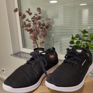 Svarta sneakers från Björn Borg - Svarta sneakers från Björn Borg i textil med vita detaljer och vit sula. Klassisk låg modell med snörning och rund tå. Snygg och enkel design som passar till det mesta. Märkeslogga på plösen och sidan. Perfekta för dig som gillar stilrena skor.