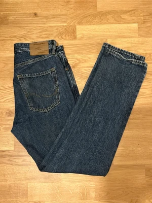 Mörkblå jeans från Jack & Jones - Säljer ett par mörkblå jeans från Jack & Jones med klassisk femficksdesign och raka ben. Jeansen har normal passform, gylf med knapp samt snygga kontrastsömmar. Perfekt för dig som gillar en enkel och tidlös look. Storlek W30 L34