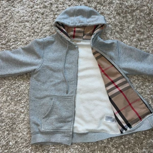 Burberry hoodie - Burberry’s grå hoodie som får fram en archive still. Den har Burberry’s ikoniska färg/ränder på insidan av koftan och i luvan.                                          OBS!  Priset är inte hugget i sten men var snäll att komma med rimliga priset.                                    Den har en super liten fläck på baksidan som syns om man kollar tydligt men var snäll och läsa igenom allt detta innan köp. 