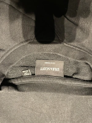 Svart sweatshirt från Lyle & Scott - Svart sweatshirt från Lyle & Scott med klassisk rund hals och långärmad passform. Tröjan har en gul broderad logga på bröstet och är tillverkad i mjuk bomull. Perfekt för dig som gillar stilrena och enkla plagg med en touch av street.