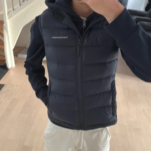 Peak performance väst - Snygg mörkblå dunväst från Peak Performance i storlek S. Västen har quiltad design, dragkedja framtill och två sidofickor. Perfekt att slänga över en hoodie för extra värme. Diskret logga på bröstet och stilren look. Väldigt bra pris för att vara i detta skick, Nyrpis≈2100 