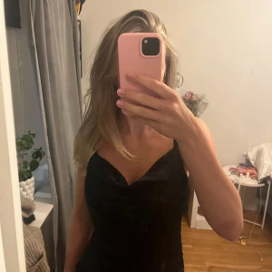 Svart linnetopp från Kappahl - Säljer en svart linnetopp från Kappahl med tunna axelband och snygg draperad urringning. Toppen har en lätt glansig yta och justerbara axelband för perfekt passform. Perfekt att styla med jeans eller kjol för en trendig look.