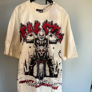 Hellstar Studios t-shirt med tryck - Cool t-shirt från Hellstar Studios i offwhite med stora grafiska tryck fram och bak i svart och rött. Oversized passform, korta ärmar och rund hals. Trycken har edgy motiv med text och illustrationer, perfekt för dig som gillar streetwear med attityd.