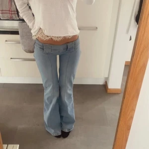 Ljusblå bootcut jeans låg midja - Säljer ett par ljusblå jeans med bootcut-modell och låg midja. Jeansen har klassisk femficksdesign, bälteshällor och är tillverkade i ett mjukt denimtyg. Perfekta för dig som gillar retro vibe och vill ha en snygg siluett. Är avklippta längst ner passar mig som är 166