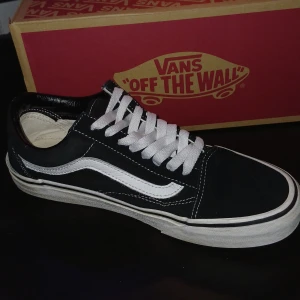 Vans Old Skool Black/White EUR 40 - Klassiska Vans Old Skool sneakers i svart och vitt med den ikoniska vita sidoremsan. Skorna har vit snörning, platt gummisula med våffelmönster och ovandel i canvas och mocka. Perfekta för en streetwear-look och passar till det mesta.
