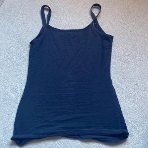 Mörkblå linnetopp från Intimissimi - Säljer en stilren mörkblå linnetopp från Intimissimi med smala axelband och rundad halsringning. Toppen är gjord i mjuk bomull och har en enkel, tight passform som sitter snyggt mot kroppen.  Passar till alla outfits.