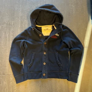 Vintage hollister cardigan/hoodie! - Skit snygg tröja/jacka av märket hollister i perfekt vintage skick. Den är använd så klart men fortfarande i fantastiskt skick.Tröjan är i storlek L men skulle snarare säga att den passar M/L.  Tveka inte att höra av dig med frågor och funderingar och kolla även gärna in mina andra annonser så kan vi säkert fixa ett schysst paketpris🤩🤩  Mått: Bredd: 52cm Längd: 64cm