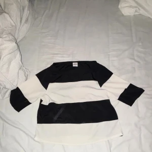 Randig svartvit topp från Weekday - Säljer en snygg topp från Weekday med breda svarta och vita ränder. Modellen har trekvartsärm och en avslappnad passform. Perfekt för dig som gillar enkel men stilren design. Materialet känns mjukt och skönt mot huden.