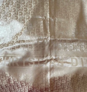 Champagnefärgad Dior halsduk i satin och chasmere - Lyxig halsduk från Christian Dior i champagnefärgad satin med diskret monogrammönster och logotyp längs kanten. Snyggt glansig finish och mjuk känsla, perfekt för att lyfta din outfit med exklusiv vibe.