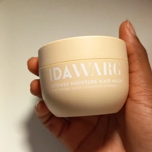 IDA WARG Intense Moisture Hair Mask - Intense Moisture Hair Mask från IDA WARG i en rund, beige plastburk på 100 ml. Masken är 100% vegansk och har en ultra hydrerande formula. Snygg minimalistisk design med vit text och lock. Perfekt för dig som vill ge håret extra fukt och vård.