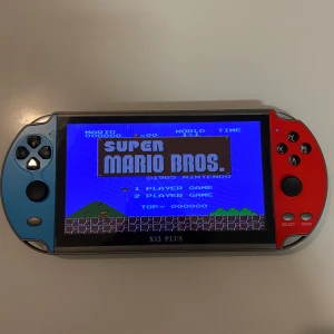 X12 Plus Spel - Retro spelkonsol med stor färgskärm, stöd för klassiska spel som Super Mario Bros och Metal Slug. Levereras med laddkabel och hörlurar. Konsolen har tydliga knappar och är i gott skick utan slitage. Perfekt för retrospel och portabelt spelande. PRISET KAN DISKUTERAS.