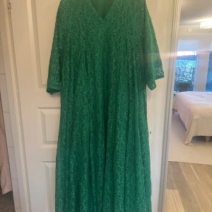 Grön lång spetsklänning med v-ringning - Säljer en grön långklänning med v-ringad hals och trekvartsärm. Klänningen är gjord i vacker spets med ett detaljerat mönster och har ett luftigt fall. Perfekt för dig som vill sticka ut med färg och elegans. Spetsen ger en lyxig känsla och klänningen har en loose passform.