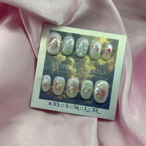 Xmas 🎄(XS);Short Oval - Superfina handgjorda press-on naglar i  XS: 14 mm, 11 mm, 11,5 mm, 10 mm, 8 mm med ljusrosa bas, iriserande glitter, stjärnor och juliga motiv som granar och rosetter. Naglarna har en kort oval form och skimrar i rosa, grönt och silver. Perfekt för dig som vill ha unika och kreativa naglar utan att gå till salong.