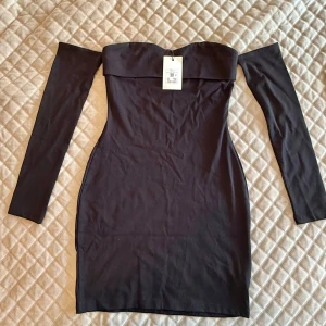 Bik Bok offshoulder klänning  - Supersnygg svart offshoulder klänning från Bik Bok i figurnära modell. Klänningen är kort, har långa ärmar och en bred kant upptill som ger en cool och stilren look. Perfekt för dig som gillar minimalistisk och trendig stil.