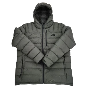 Grå dunjacka från The North Face men XL - Snygg grå dunjacka från The North Face med huva och svarta dragkedjor. Jackan är quiltad och har en normal passform, perfekt för kalla dagar. Utrustad med flera fickor och diskret logga på bröstet. Klassisk och stilren design som funkar till det mesta.