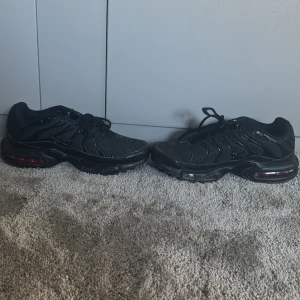 Nike Air Max Plus Tn helsvarta sneakers - Säljer ett par helsvarta Nike Air Max Plus Tn sneakers med klassisk vågig design och synlig Air Max-dämpning i sulan. Fick vid julafton men inte kommit till användning mycket alls. Slängde tyvärr boxen samma dag jag fick dom men jag kan lägga dom i en annan sko låda. Använd 2 gånger ute. Storlek 42. 