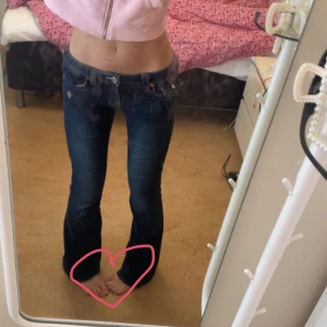 True Religion Joey Low Rise Flare Jeans - Säljer ett par mörkblå True Religion Joey jeans med låg midja och flare/bootcut. Säljer då jag inte tycker de sitter bra på mig i RÖVEN 🥺😖. En knapp saknas på ena bakfickan men det är inte något man märker. Annars är de i fint skick!