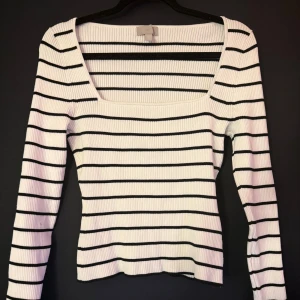 Randig ribbad tröja från H&M - Säljer en vit och svart ribbad tröja från H&M med smickrande fyrkantig ringning och lång ärm. Tröjan är figurnära och har ett klassiskt randigt mönster. Perfekt för dig som gillar stilrena och trendiga basplagg.