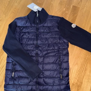 Moncler cardigan - Säljer denna sprillans nya moncler cardigan i strl M. Helt ny med tags. Kvaliten är sjukt bra + att QR kod och nfc funkar. Perfekt nu till höstens kallare dagar. Har även en svart i strl L i min profil. Bara att skriva ett DM vid intresse/frågor!