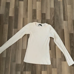 Vit ribbad långärmad topp FB Sister - En basic vit långärmad topp från FB Sister i storlek S. Toppen är ribbad och har en rund halsringning. Perfekt att styla med jeans eller kjol för en clean look.