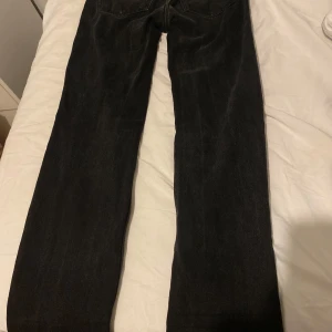Svarta raka jeans - Säljer ett par svarta jeans med rak passform. Jeansen har klassisk femficksdesign och är tillverkade i ett robust denimtyg. Perfekta för dig som gillar en enkel och stilren look.