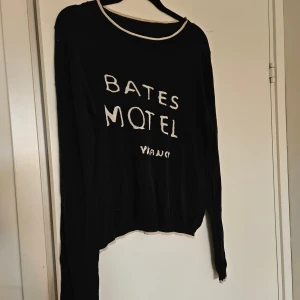 Stickad tröja i 100% silke - Superfin tunn, svart stickad tröja i 100% silke. Svart med vit text 'Bates Motel Vacancy'. Fint skick. Litet ihoosytt hål på baksidan som knappt syns. Storlek L skulle jag uppskatta