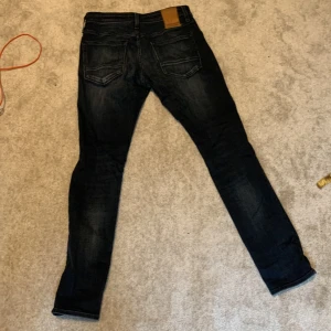 Jack & Jones Slim Glenn jeans mörkblå - Mörkblå jeans från Jack & Jones, modell Slim Glenn. Snygg slim fit med klassisk femficksdesign och diskreta slitningar. Jeansen är tillverkade i stretchig denim för en bekväm passform och har normal midja.