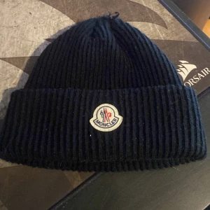 Moncler mössa - Passformen är onesize, självaste längden av mössan är kort. Vene ifall den är äkta eller inte då den är köpt av en kompis, oavsett riktigt snygg. Lite sömmar som har dykt upp på toppen av mössan men inga hål.