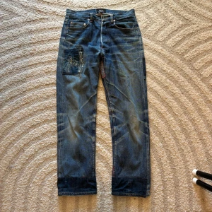 A.P.C. jeans med patchwork och slitningar - Unika blå jeans från A.P.C. med coola patchwork-detaljer och slitningar på både fram- och baksida. 