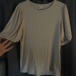 Beige ribbad topp från Object - Säljer en beige ribbad topp från Object med puffiga korta ärmar och rund halsringning. Jätte fin men säljs för att den inte kommer till användning. Kontakta för egna bilder.