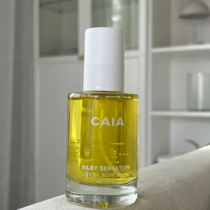 CAIA Silky Sensation Dry Oil Body Serum - CAIA Silky Sensation Dry Oil Body Serum i färgen warm amber. Kommer i en genomskinlig glasflaska med vit pump och tillhörande beige kartong. Innehåller lingonfröolja och samphiraolja för en silkeslen känsla på huden.