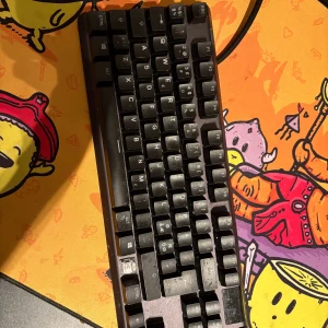 SteelSeries Apex PRO TKL - SteelSeries Apex PRO TKL mekaniskt tangentbord. Kompakt design, RGB-belysning (ej synlig på bild). Vissa tangenter visar tydligt slitage och en tangent saknas. Perfekt för gaming eller kontorsbruk. Funktionstestad och fullt fungerande.