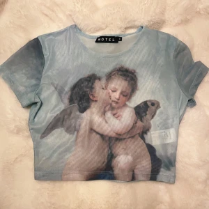  topp med änglamotiv från Motel - Säljer en mesh topp från Motel i ljusblått med ett klassiskt änglamotiv framtill. Storlek S💓