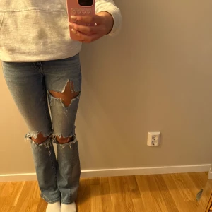 Ljusblå slitna bootcut jeans - Säljer ett par ljusblå jeans med stora slitningar över knäna och bootcut-ben. Det är från american eagels och går inte att köpa längre💞 Jag är 170cm och har ofta 32-34 och 25-27 och xs-s för referens!