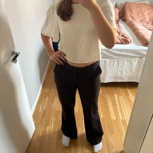 Mörkbruna kostymbyxor - Ett par mörkbruna kostymbyxor från Gina tricot. Lågmidjade, relaxed bootcut modell i storlek 40 (passar mig som har M/38 i vanliga fall). Pressveck, dragkedjegylf bälteshällor och fickor i sidorna. Sparsamt använda så därför mycket gott skick!🤗