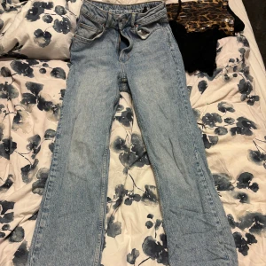 Ljusblå jeans straight fit - Klassiska jeans i ljusblå denim med raka ben och hög midja. Jeansen har fickor, knappgylf och ikoniska bakfickor. Perfekta för en avslappnad och tidlös stil.