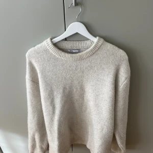 Beige stickad tröja från Zara XL - Mysig beige stickad tröja från Zara i storlek XL. Tröjan har rund halsringning, ribbade muddar och en klassisk, enkel design som är lätt att matcha. Perfekt för lager-på-lager under kyliga dagar. Står xl som storlek men passar M och L bättre