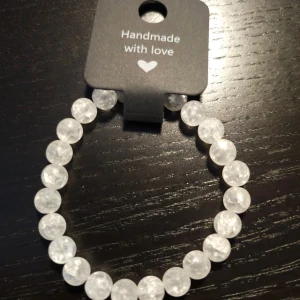 Handgjort vitt pärlarmband - Snyggt handgjort armband med runda, frostade krackelerade vita pärlor. Pärlorna har en cool look som ger armbandet en fräsch och stilren vibe. Perfekt att matcha med andra smycken eller bära som det är för en clean look. Ca 17cm 