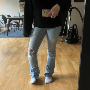 Ljusblå bootcut jeans med slitningar - Säljer ett par ljusblå bootcut jeans, de är lowwaist  och har slitningar. Midjemått:38cm Innerbenslängd:81cm