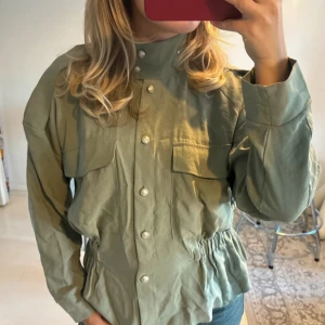 Grön skjorta med dragkedja från Zara - Snygg grön skjorta från Zara med hög krage, dragkedjedetalj och pärlknappar. storlek xs💚💚