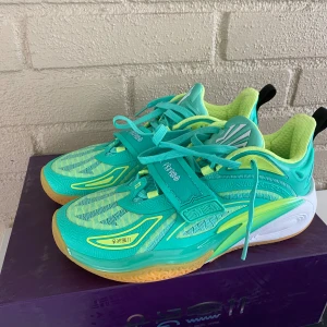Anta Kai 1 green grails basketskor - Säljer ett par Anta Kai 1 från Kyrie Irving i turkos och limegrönt med coola detaljer och mönstrad sula i gult och grönt. Skorna har snörning, kardborreband och är tillverkade i syntetmaterial med mesh för extra andningsförmåga. Perfekta för dig som vill sticka ut på basketplanen. De är oanvända. Orginalbox medföljer.