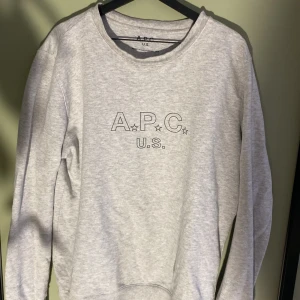 Grå sweatshirt från A.P.C. U.S. - Grå sweatshirt från A.P.C. U.S. med tryckt logga framtill. Två små hål på vänsta inne arm som man inte ser, väldigt sällsynt tröja.