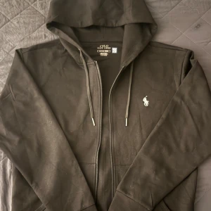 Svart hoodie från Polo Ralph Lauren - Svart zip up hoodie från Polo Ralph Lauren, helt ny. Använd 1 gång. Kom med bud och dm för mer info och bilder!