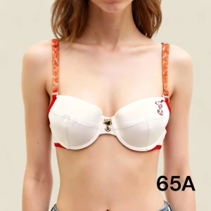 Ny vit och röd Snoopy BH med etiketten kvar - Här kommer en klassiker från tidigt 2000-tal tillbaka. Supersöt behå i vitt med röda detaljer och Snobben-tryck på ena kupan. De avtagbara axelbanden är halvtransparenta i orange färg och lite plastigt material. Axelbanden har Snoopy-motiv och justerbara spännen. Bhn har en liten berlock föreställande Snobben i silver mellan kuporna. Den har uttagbara tunna kuddar, men är inte en pushup. Den är gjord av 95% bomull och 5% elastan. Rabatt vid flerköp. Finns fler storlekar, bara fråga.