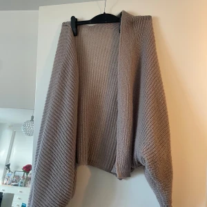 Beige oversized stickad kofta - Mysig oversized kofta i beige stickat material. Koftan har en öppen front och breda, långa ärmar.