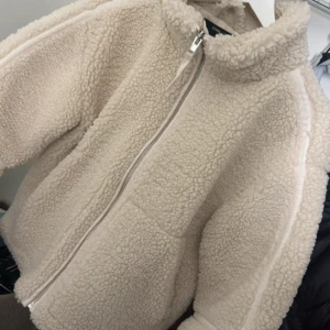  Teddyjacka  - Mysig och trendig teddyjacka cremefärgad med hög krage och hel dragkedja framtill. Jackan har en oversized passform och är tillverkad i fluffigt fleece-material som håller dig varm under kyliga dagar. Köpt i Grekland från en butik som heter Sinsay. Har mycket bra skick då jag knappt använt den.
